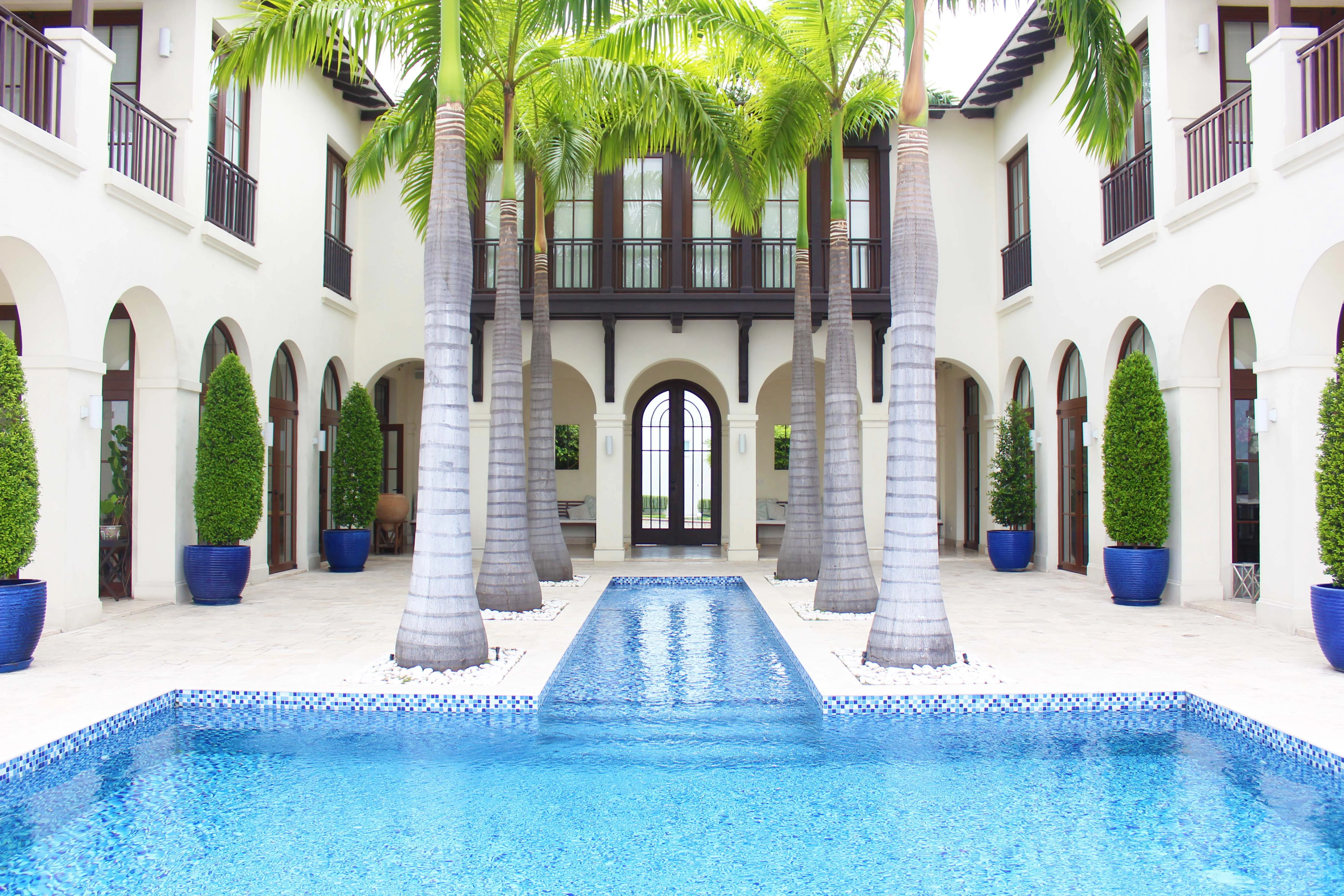 Patio central con palmeras, arcos y láminas de agua