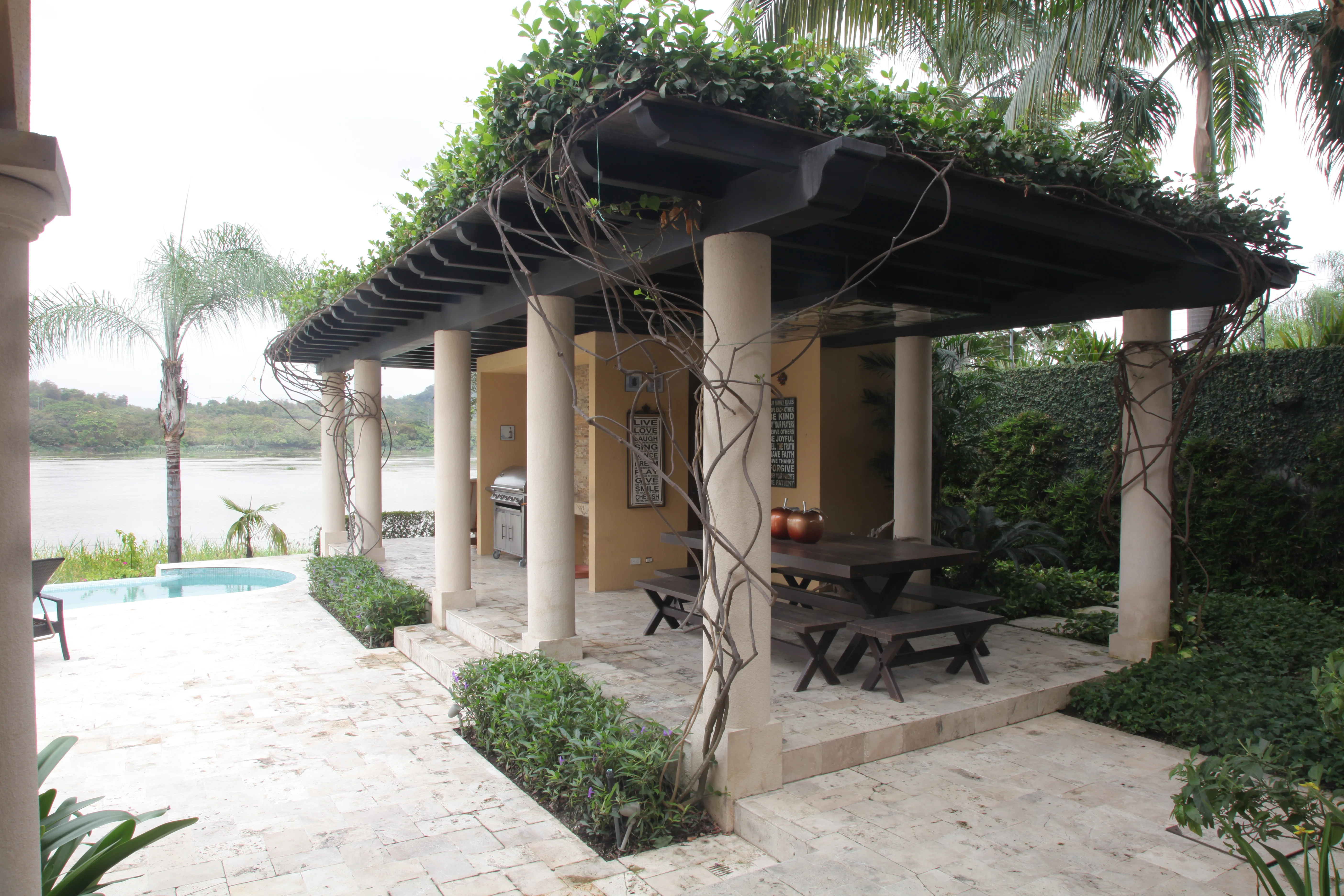 Terraza cubierta por una pérgola entre jardines